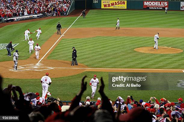 Jimmy Rollins, Shane Victorino and Chase Utley of the Philadelphia Phillies all run towards home plate as they scored on a 3-run home run in the...