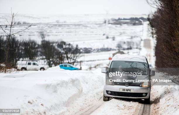 Cars navigate snowy condition in Kirklees, Yorkshire.