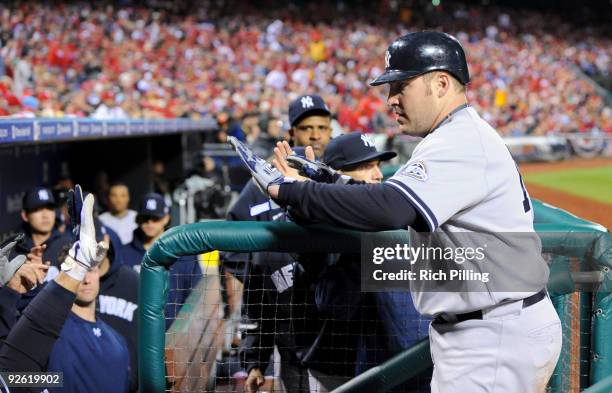 Eric Hinske of the New York Yankees is congratulated by teammates as he returns to the dugout after scoring in the top of the fifth inning of Game...