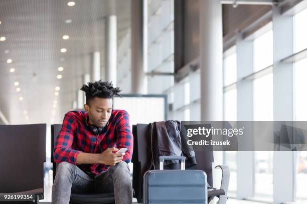 jonge afrikaanse gebruik mobiele telefoon in luchthaven lounge - passenger muzikant stockfoto's en -beelden