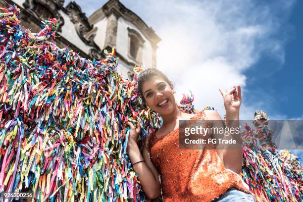 woman making a wish with brazilian ribbons on church fence in salvador, bahia, brazil - louvar religião imagens e fotografias de stock
