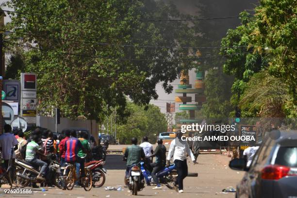 People watch as black smoke rises as the capital of Burkina Faso came under multiple attacks on March 2 targeting the French embassy, the French...