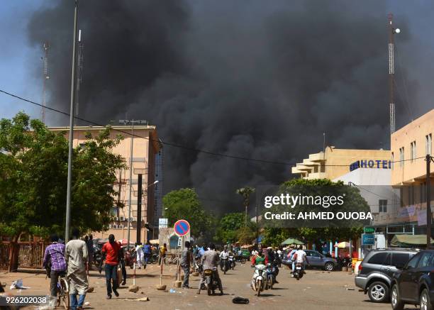 People watch as black smoke rises as the capital of Burkina Faso came under multiple attacks on March 2 targeting the French embassy, the French...