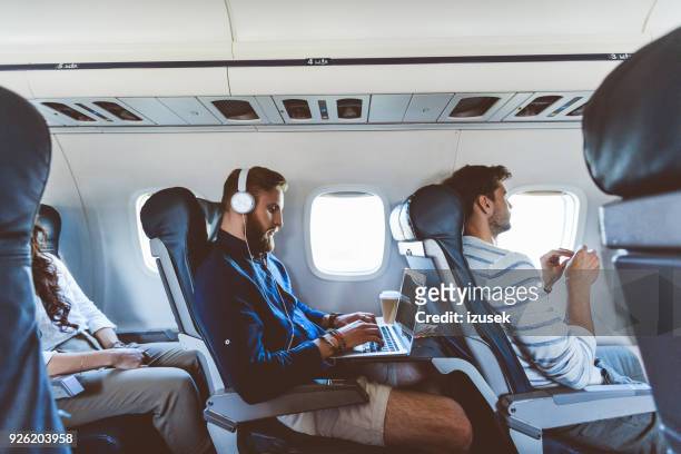 pasajero masculino usando laptop durante el vuelo - avión fotografías e imágenes de stock