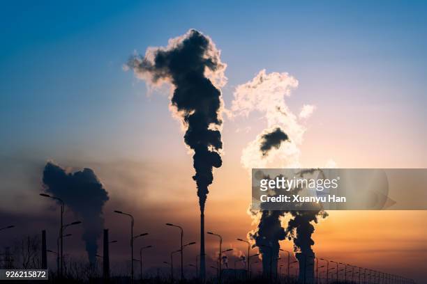 silhouette of a high industrial pipe with the sun behind it - broeikasgas stockfoto's en -beelden
