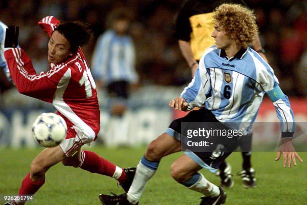 Qu Bo , of China, fights for the ball with Fabricio Coloccini, of Argentina, 27 June 2001, during a match at the Velez stadium, in Buenos Aires, for...