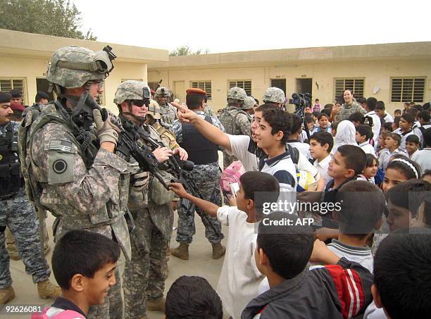 Iraqi school children jest with US soldiers after members of the Iraqi military Volcano Brigade in charge of the Bayaa district of the capital...