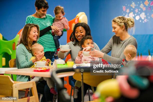 het nemen van een pauze van het afspeelgebied - baby group stockfoto's en -beelden