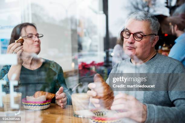 senior couple eating in a small local bakery shop. - senior women cafe stock pictures, royalty-free photos & images