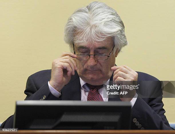 Former Bosnian Serb leader Radovan Karadzic adjusts his glasses during his first court appearance since the start of his genocide trial in the...