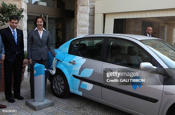 French Minister of Foreign Trade Anne-Marie Idrac charges an electric-powered vehicle on October 22, 2009 in Jerusalem after a meeting with Shai...