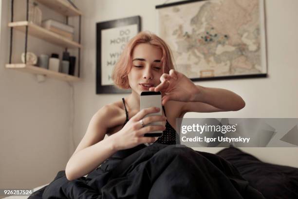 young woman takes a picture - young woman using smartphone at home stock-fotos und bilder