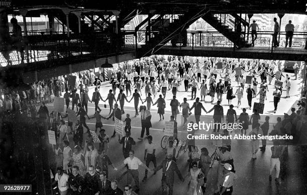 Demonstrators and Chicago Freedom Movement members march in lines, some with posters, under the Chicago El during a protest calling for the firing of...