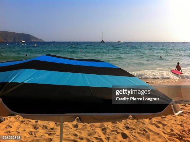 typical beach umbrella on the corsican beach of arone, along the highway d824 near porto, corsica, france - corsican flag stock pictures, royalty-free photos & images