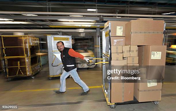 Deutsche Post AG employee Rihan Guendogdu pulls a cart full of parcels at a package sorting center in Aschheim, near Munich, Germany on Tuesday, Nov....