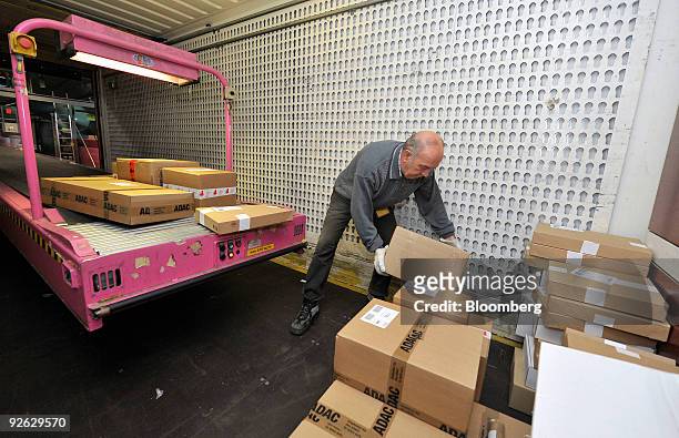 An employee loads sorted parcels onto a conveyor belt for delivery at a Deutsche Post AG package sorting center in Aschheim, near Munich, Germany on...