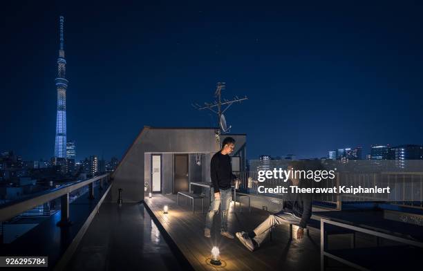 two friends are hanging out on the rooftop with tokyo skytree at the background - tokyo sky tree stock-fotos und bilder