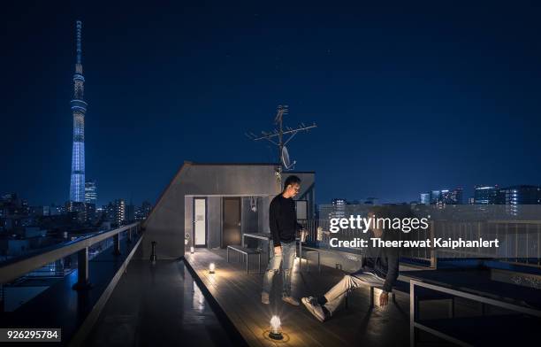 two friends are hanging out on the rooftop with tokyo skytree at the background - rooftop party night stock pictures, royalty-free photos & images