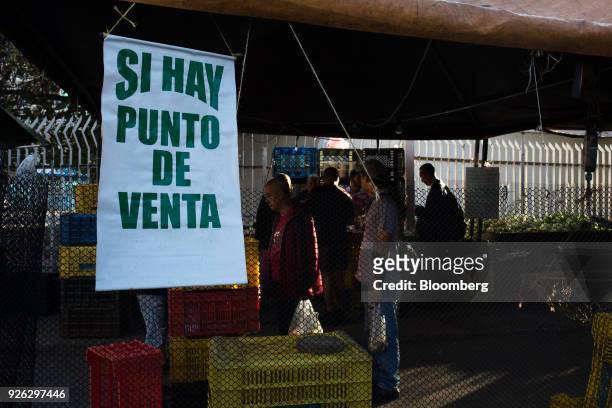 Sign notifying customers that they accept debit cards hangs on display outside a vegetable stand in Caracas, Venezuela, on Thursday, March 1, 2018....