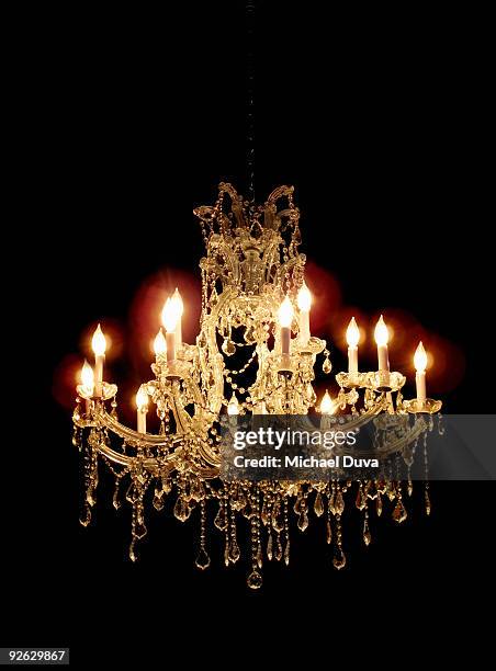 glowing chandelier hanging in darkness - chandeliers foto e immagini stock