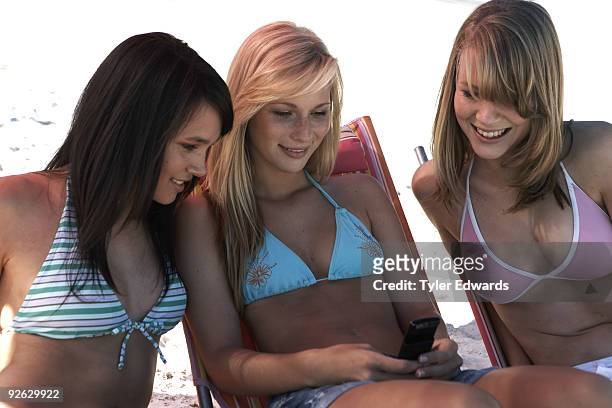 three girls reading text message on mobile phone - 3 teenagers mobile outdoors stockfoto's en -beelden