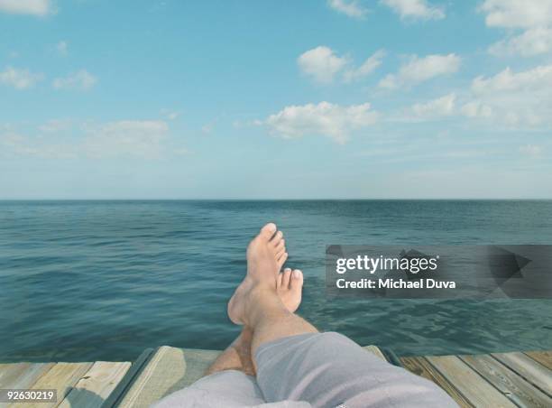 detail of feet relaxing on chair in front of water - boat deck stock pictures, royalty-free photos & images