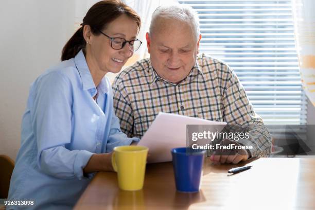 hombre anciano y cuidador leer documentos - form filling fotografías e imágenes de stock