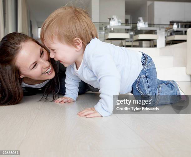 mother and baby laughing crawling on floor - crawling stock pictures, royalty-free photos & images