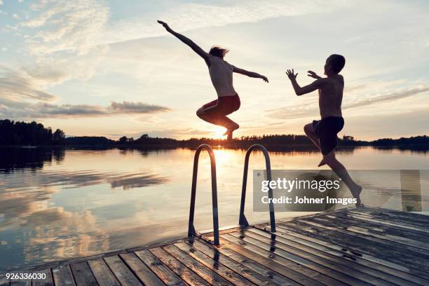 boys jumping into lake - bathing in sunset stockfoto's en -beelden