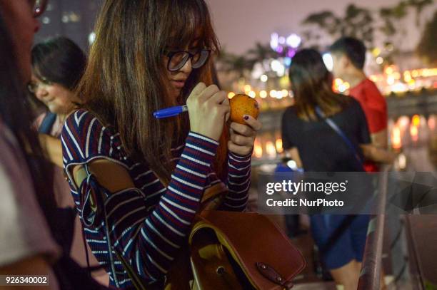 Malaysian ethnic Chinese women writes her wishes and phone number on the mandarin orang before throwing into the lake, marking the end of Chinese New...