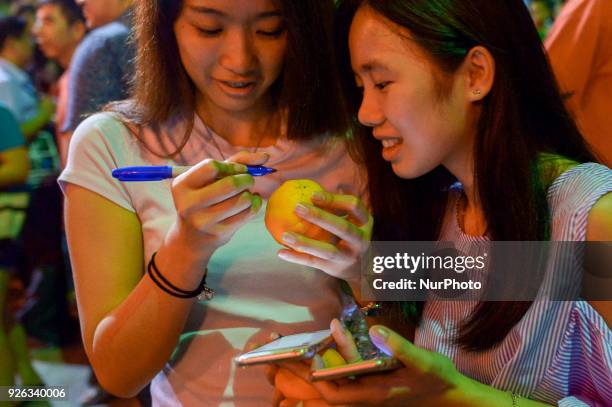 Malaysian ethnic Chinese women write their wishes and phone number on the mandarin orang before throwing into the lake, marking the end of Chinese...