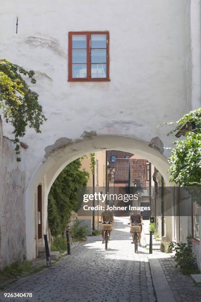 couple cycling through old town - stockholm old town stock pictures, royalty-free photos & images