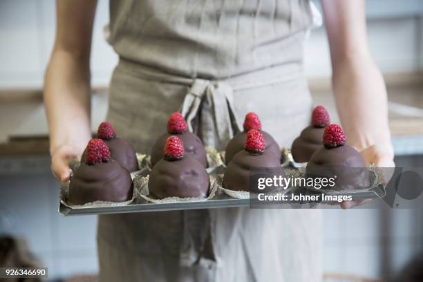person holding chocolate cookies with raspberries on tray - cake sale stock-fotos und bilder