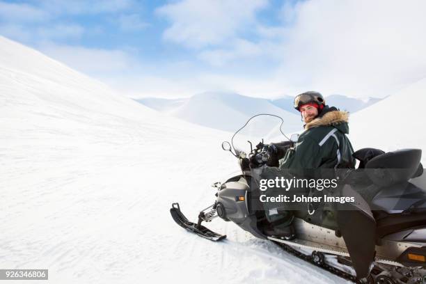 man sitting on snowmobile - isole svalbard foto e immagini stock