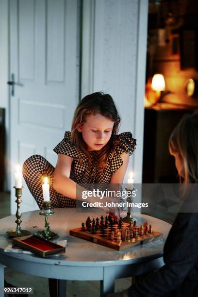 two girls playing chess in living room - family game night stock-fotos und bilder