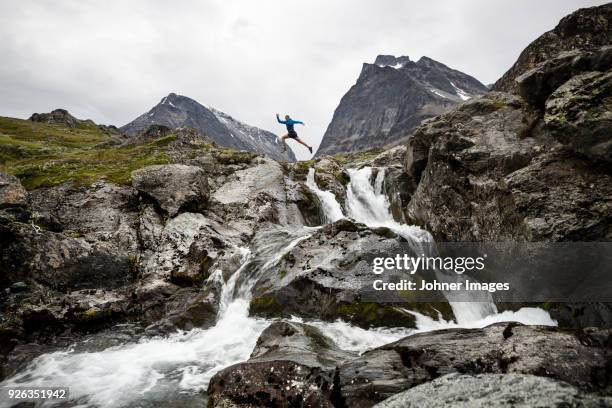 person jumping over mountain river - stroomversnelling stockfoto's en -beelden