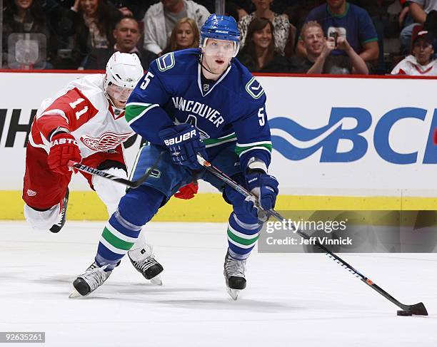 Dan Cleary of the Detroit Red Wings tries to check Christian Ehrhoff of the Vancouver Canucks as he skates up ice during their game at General Motors...