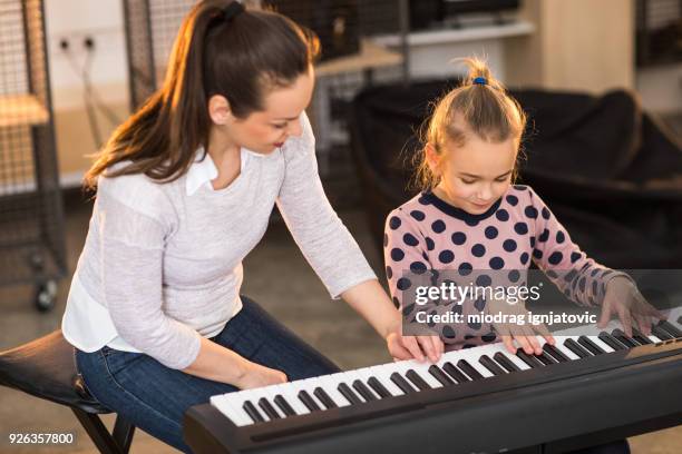 teacher showing to a child how to play piano - electric piano stock pictures, royalty-free photos & images