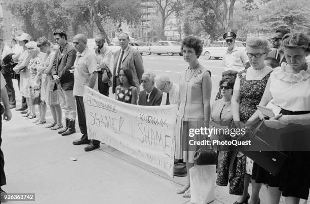 On the sidewalk in from of the White House, protesters bow their heads and kneel in prayer as they protest American involvement in the Vietnam War,...