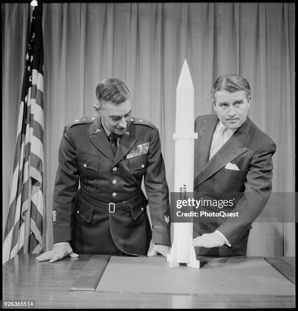 View of chief of the Army Ballistic Missile Agency Major General John B Medaris and rocket scientist Dr Wernher von Braun as they pose with a scale...