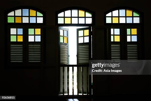 light coming through old shop house stained glass windows. - light coming through doors stock-fotos und bilder