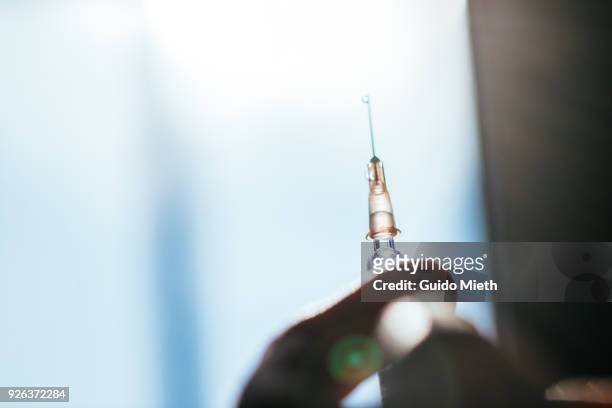 hand holding syringe in backlight. - drugsmisbruik stockfoto's en -beelden