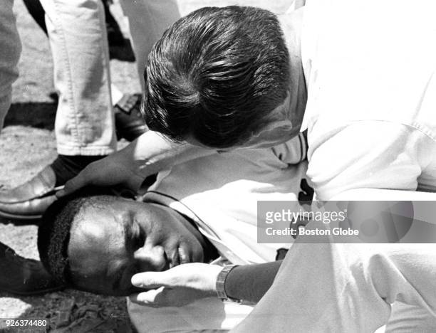 Boston Red Sox trainer Buddy Le Roux looks at player George Scott after he got hit above the left eye after a batted ball took a bad hop during a...