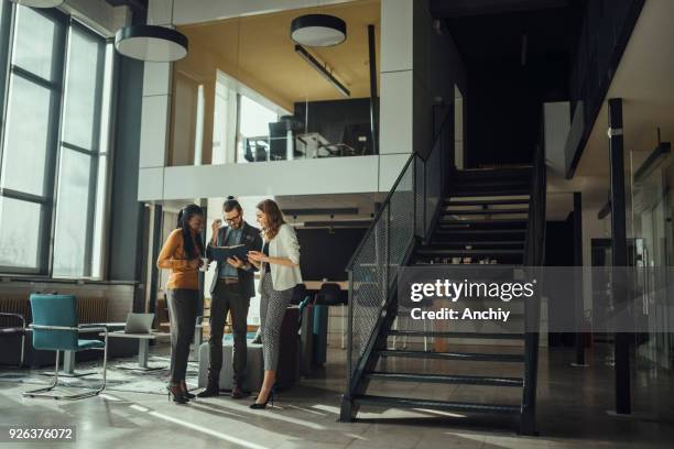 colleagues looking over business plan in a lobby - free trade hall stock pictures, royalty-free photos & images