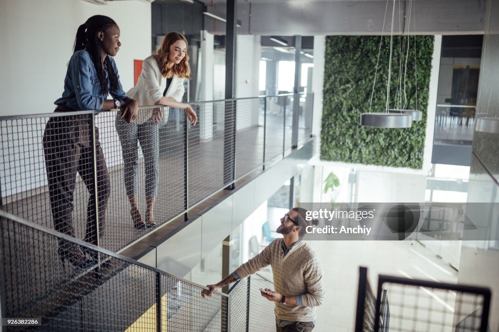 Businessman climbing the stairs and talking to his female coworkers