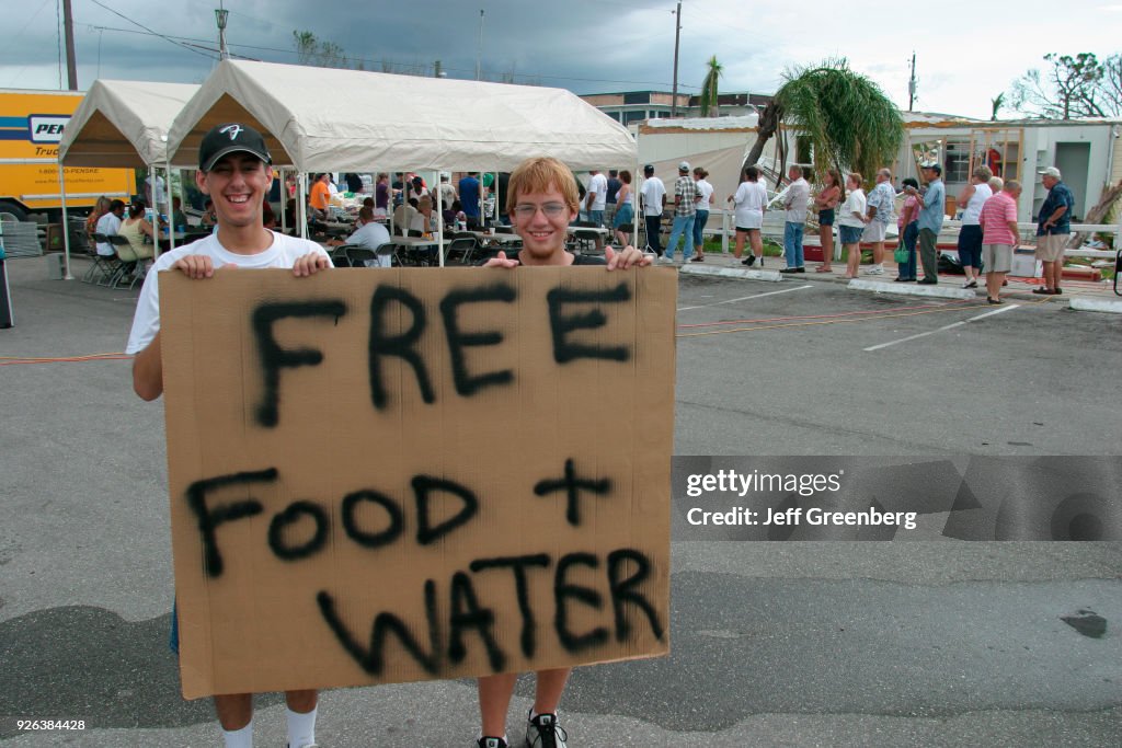 Two boys holding a free food and water sign at Port Charlotte after Hurricane Charley damage.