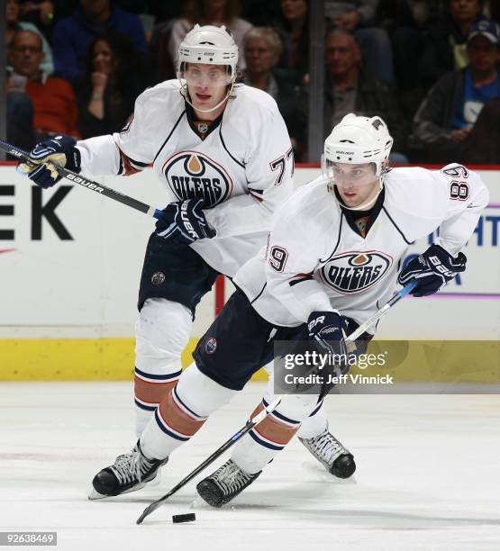 Tom Gilbert of the Edmonton Oilers looks on as teammate Sam Gagner skates up ice with the puck during their game against the Vancouver Canucks at...