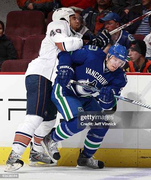 Theo Peckham of the Edmonton Oilers checks Christian Ehrhoff of the Vancouver Canucks during their game at General Motors Place on October 25, 2009...