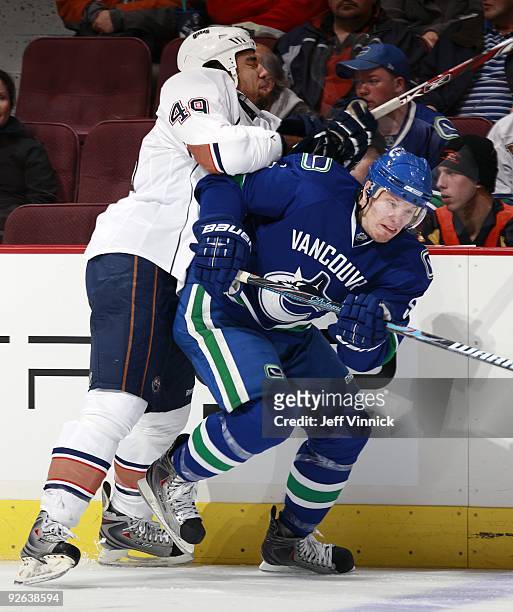 Theo Peckham of the Edmonton Oilers checks Christian Ehrhoff of the Vancouver Canucks during their game at General Motors Place on October 25, 2009...