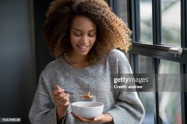 woman eating a bowl of cereals at home - bowl of cereal stock pictures, royalty-free photos & images